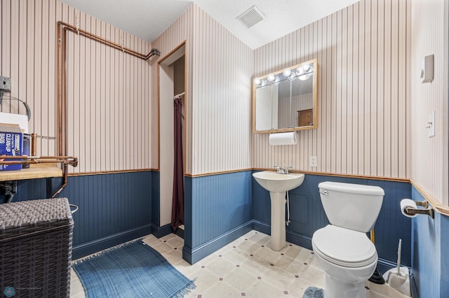 18000 10th St SW, Hawley, MN 56549 - bathroom with wainscoting, wallpapered walls, toilet, a shower with shower curtain, and a sink