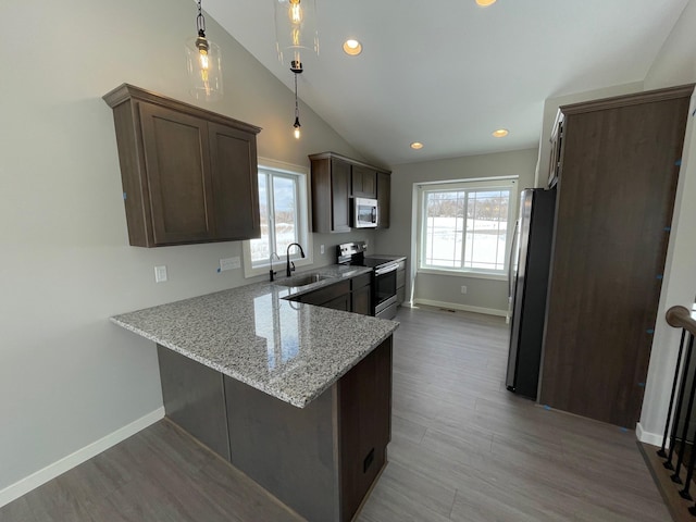 32755 Naples St NE, Cambridge, MN 55008 - kitchen with stainless steel appliances, a sink, dark brown cabinetry, light stone countertops, and a peninsula