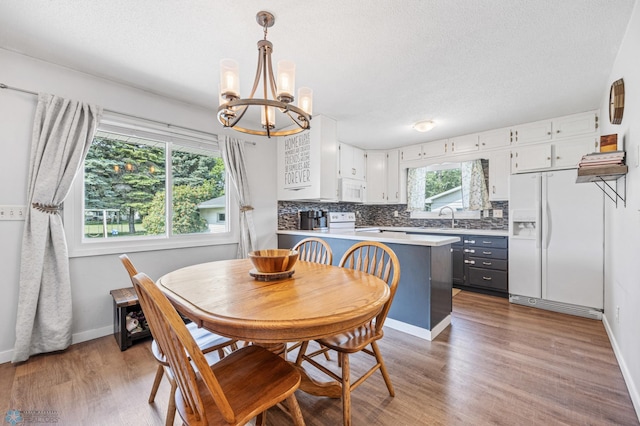 1311 Joseph St, Hawley, MN 56549 - dining room featuring a chandelier, wood finished floors, a textured ceiling, and baseboards