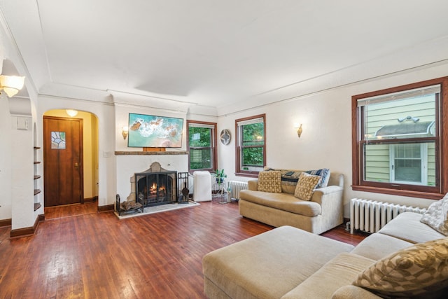 5705 36th Ave S, Minneapolis, MN 55417 - living area featuring radiator, wood-type flooring, arched walkways, a warm lit fireplace, and ornamental molding