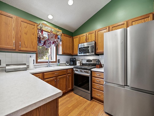 201 3rd St NW, Saint Michael, MN 55376 - kitchen with appliances with stainless steel finishes, vaulted ceiling, a textured ceiling, light countertops, and brown cabinets