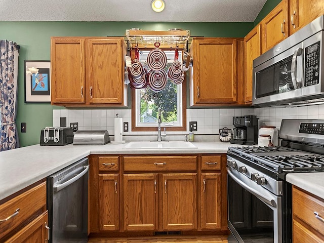 201 3rd St NW, Saint Michael, MN 55376 - kitchen featuring appliances with stainless steel finishes, light countertops, tasteful backsplash, brown cabinets, and a textured ceiling