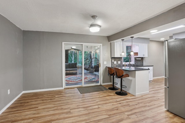1985 Mabel Ct, Chaska, MN 55318 - kitchen featuring freestanding refrigerator, dark countertops, white cabinets, light wood-type flooring, and a textured ceiling