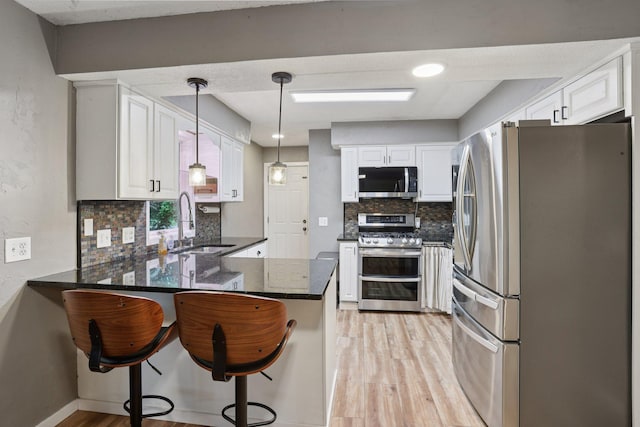 1985 Mabel Ct, Chaska, MN 55318 - kitchen featuring appliances with stainless steel finishes, a peninsula, light wood finished floors, decorative backsplash, and dark stone counters