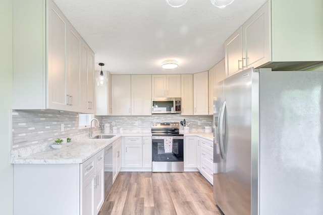 1414 5th Ave SW, Rochester, MN 55902 - kitchen featuring stainless steel appliances, a sink, light wood-style flooring, tasteful backsplash, and hanging light fixtures