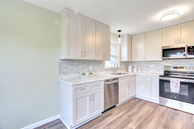 1414 5th Ave SW, Rochester, MN 55902 - kitchen with stainless steel appliances, a sink, light wood-type flooring, decorative backsplash, and a textured ceiling