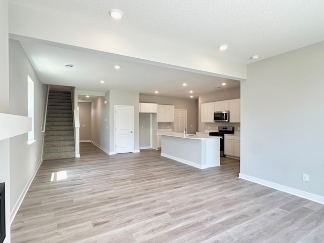 151 Snowdrop Trl, Waconia, MN 55387 - unfurnished living room featuring light wood-style flooring, stairway, and recessed lighting