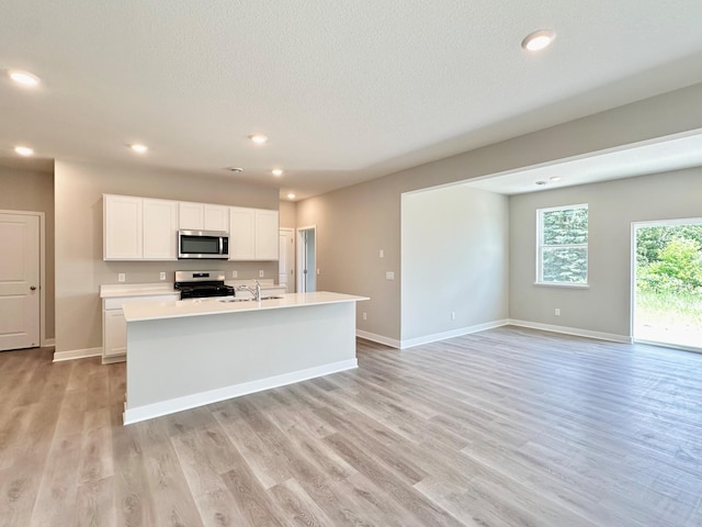 151 Snowdrop Trl, Waconia, MN 55387 - kitchen with stainless steel microwave, range with electric stovetop, light wood-style flooring, white cabinetry, and light countertops