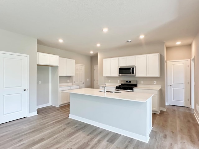 151 Snowdrop Trl, Waconia, MN 55387 - kitchen featuring appliances with stainless steel finishes, light wood-type flooring, white cabinetry, a center island with sink, and light countertops