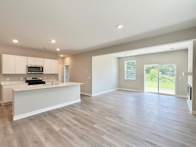 151 Snowdrop Trl, Waconia, MN 55387 - kitchen featuring stainless steel microwave, electric range oven, open floor plan, light countertops, and white cabinetry