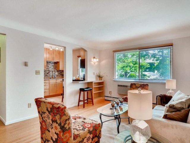 656 Ashland Ave Unit 11, Saint Paul, MN 55104 - living area with light wood-style flooring, a baseboard heating unit, arched walkways, and a wall mounted air conditioner