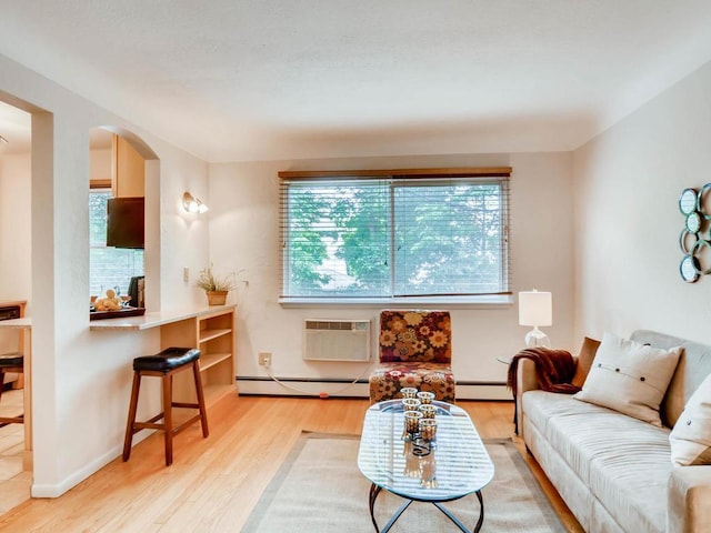 656 Ashland Ave Unit 11, Saint Paul, MN 55104 - living room with a baseboard radiator, light wood finished floors, arched walkways, and a wall unit AC