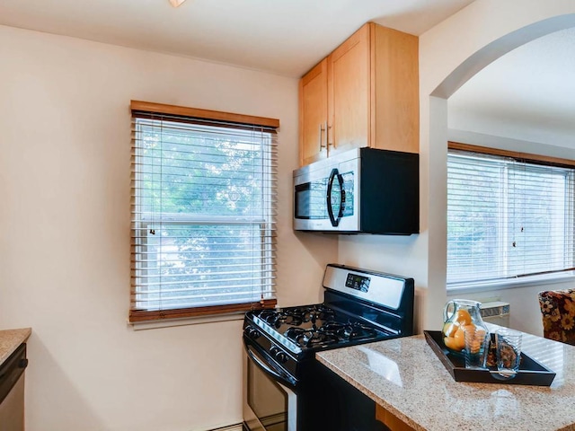 656 Ashland Ave Unit 11, Saint Paul, MN 55104 - kitchen featuring stainless steel appliances, arched walkways, light brown cabinetry, and light stone countertops