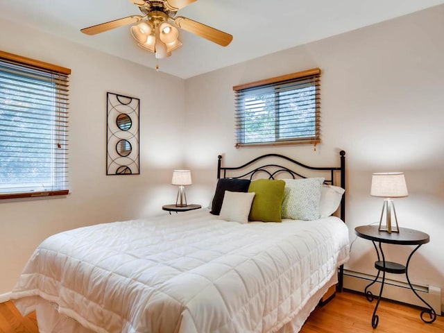 656 Ashland Ave Unit 11, Saint Paul, MN 55104 - bedroom with a baseboard heating unit, wood finished floors, and a ceiling fan