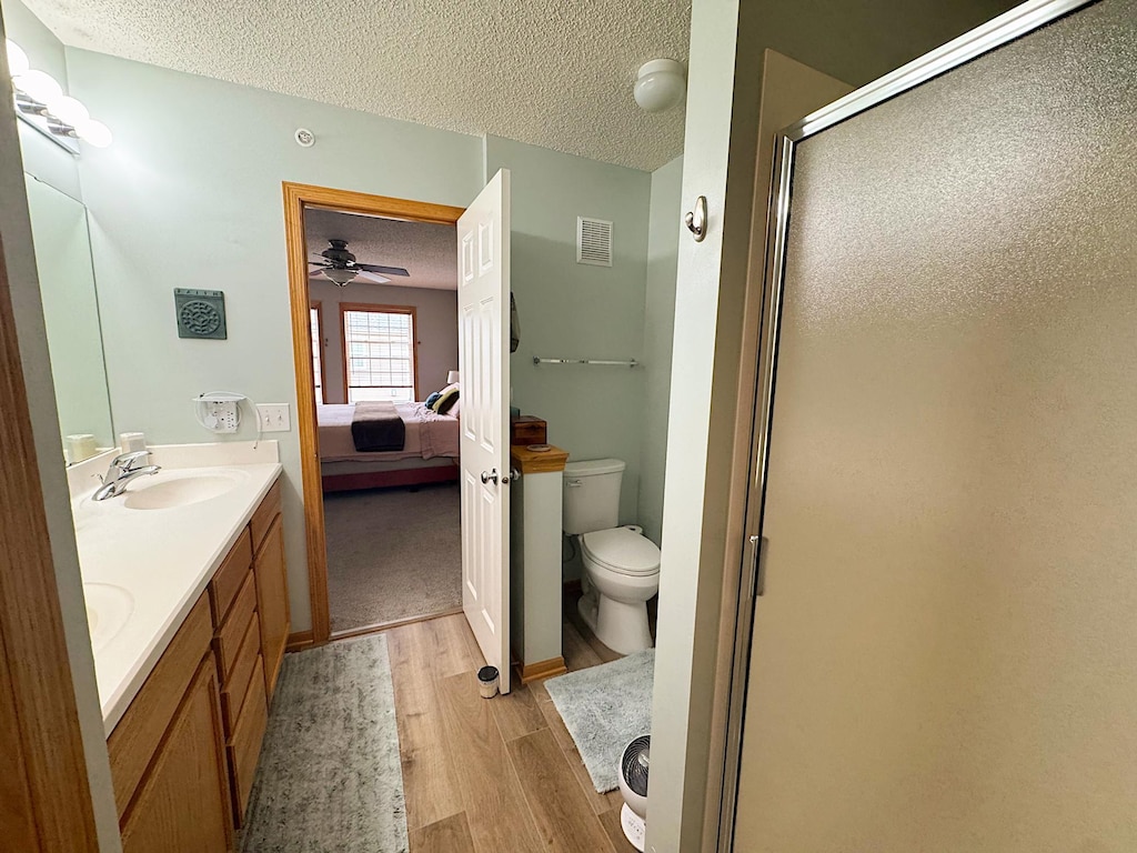 4332 Victor Path Unit 6, Hugo, MN 55038 - full bath with wood finished floors, a textured ceiling, connected bathroom, toilet, and a stall shower
