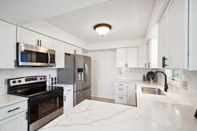 1173 Jefferson St S, Shakopee, MN 55379 - kitchen with stainless steel appliances, a sink, light stone countertops, tasteful backsplash, and white cabinets