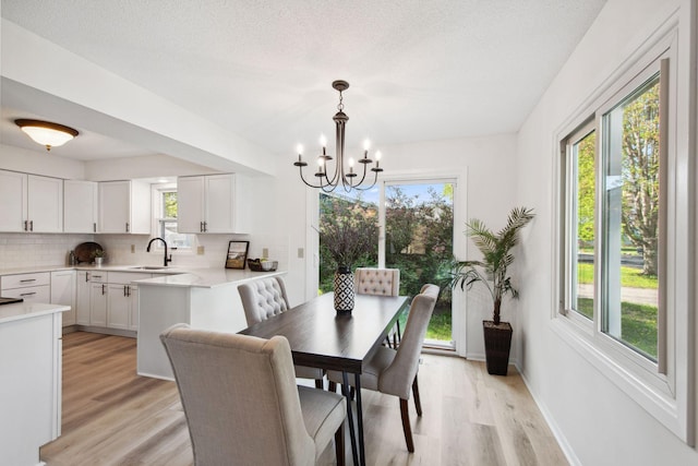 1173 Jefferson St S, Shakopee, MN 55379 - dining room featuring light wood-style flooring, a chandelier, baseboards, and a textured ceiling
