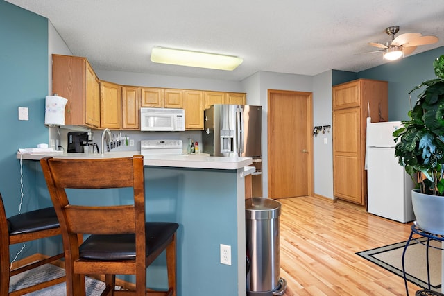 4645 Eagle Ridge Ln, Monticello, MN 55362 - kitchen with white appliances, a peninsula, light wood finished floors, a breakfast bar, and light countertops