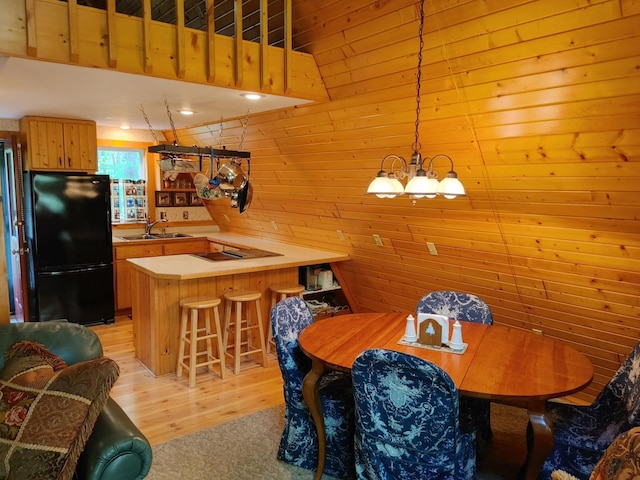76683 Long Lake Rd, Kettle River Twp, MN 55795 - dining space with a chandelier, light wood finished floors, wood walls, and bar with sink