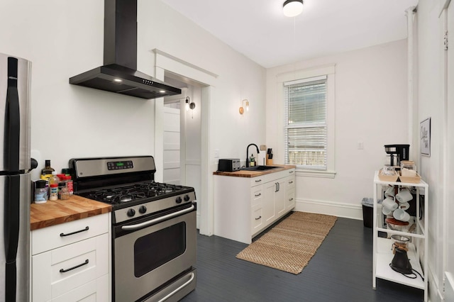 681 Dayton Ave, Saint Paul, MN 55104 - kitchen featuring appliances with stainless steel finishes, wall chimney range hood, wood counters, a sink, and white cabinetry