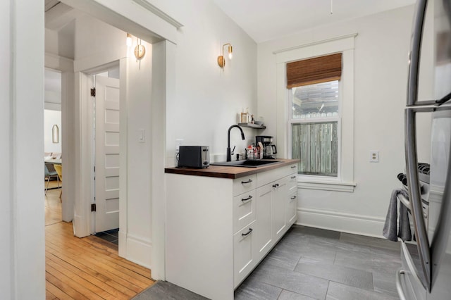 681 Dayton Ave, Saint Paul, MN 55104 - kitchen featuring a sink, wood counters, white cabinetry, and baseboards