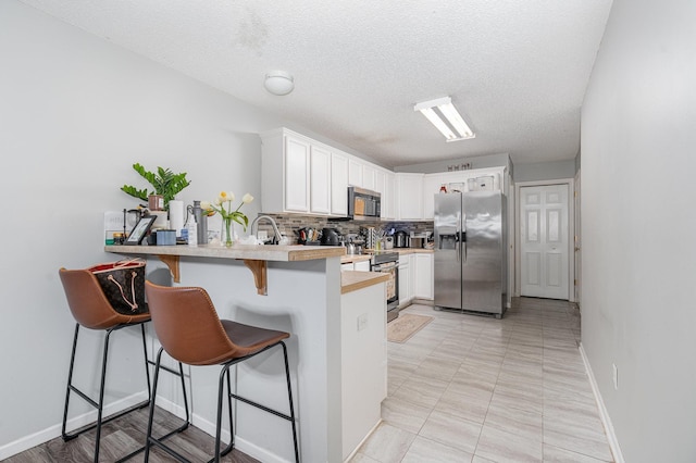 13525 Partridge Cir NW, Andover, MN 55304 - kitchen with appliances with stainless steel finishes, light countertops, a breakfast bar area, a peninsula, and white cabinets