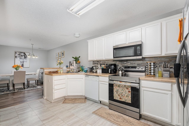 13525 Partridge Cir NW, Andover, MN 55304 - kitchen featuring stainless steel appliances, a peninsula, light countertops, backsplash, and a textured ceiling