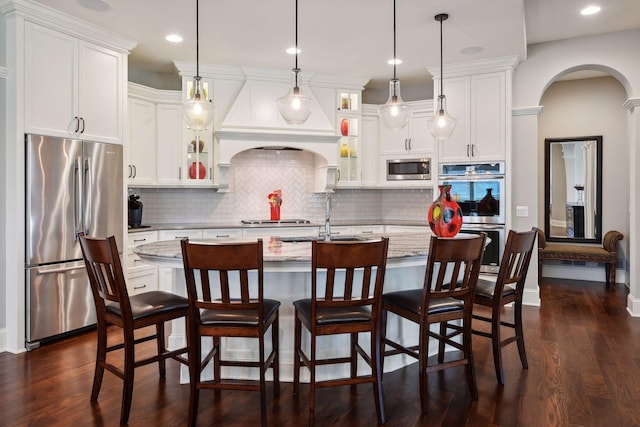 749 Fairway Dr, Medina, MN 55340 - kitchen with appliances with stainless steel finishes, a sink, dark wood-type flooring, arched walkways, and white cabinetry