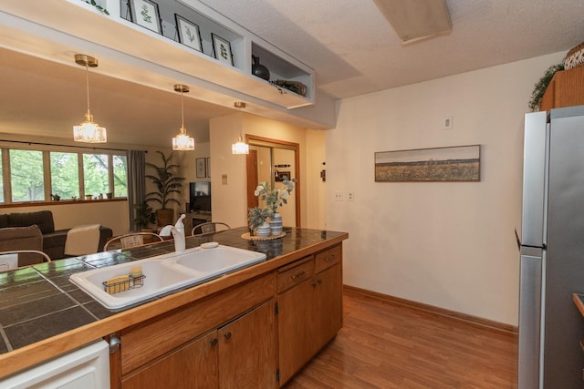 1269 Cleveland Ave N Unit 2B, Saint Paul, MN 55108 - kitchen featuring freestanding refrigerator, a sink, wood finished floors, pendant lighting, and brown cabinetry