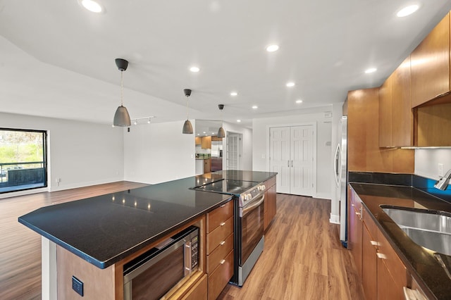 2885 Knox Ave S Unit 202, Minneapolis, MN 55408 - kitchen featuring appliances with stainless steel finishes, a sink, light wood-style flooring, a center island, and brown cabinets