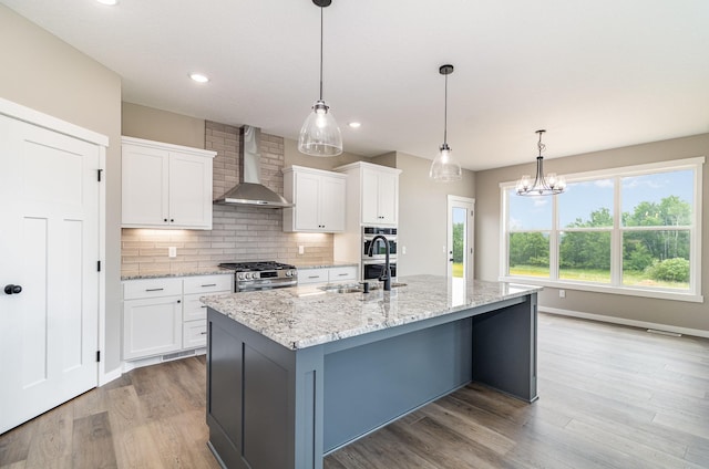 20610 Redwood St NW, Oak Grove, MN 55011 - kitchen with wall chimney range hood, stainless steel gas stove, white cabinets, an island with sink, and backsplash