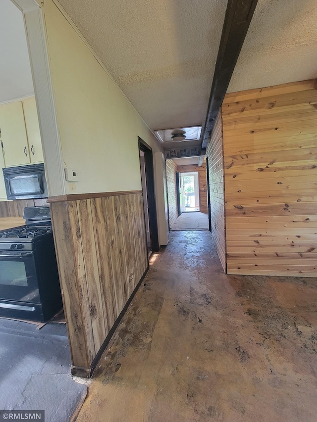 203 Ann Ave E, Clarissa, MN 56440 - corridor with wooden walls, a textured ceiling, unfinished concrete floors, and a wainscoted wall