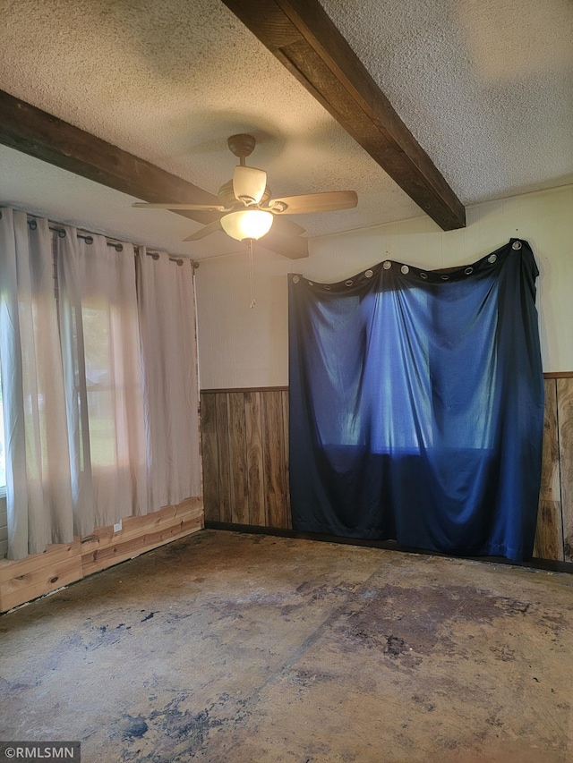 203 Ann Ave E, Clarissa, MN 56440 - spare room with a textured ceiling, a wainscoted wall, ceiling fan, beam ceiling, and wooden walls