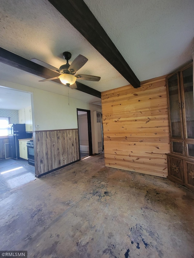 203 Ann Ave E, Clarissa, MN 56440 - unfurnished living room with wood walls, a textured ceiling, beamed ceiling, ceiling fan, and concrete floors