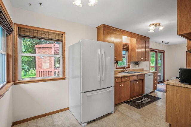 800 82nd Ave N, Brooklyn Park, MN 55444 - kitchen with white appliances, light floors, light countertops, brown cabinetry, and a chandelier