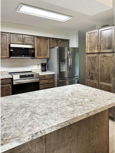 861 Lake Susan Dr, Chanhassen, MN 55317 - kitchen with stainless steel appliances, light countertops, and dark brown cabinets
