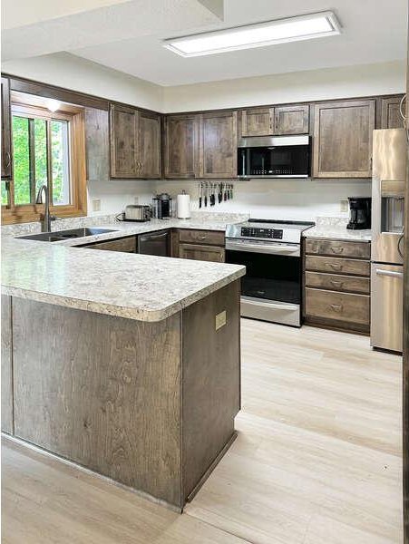 861 Lake Susan Dr, Chanhassen, MN 55317 - kitchen featuring stainless steel appliances, dark brown cabinets, light wood-type flooring, light countertops, and a peninsula