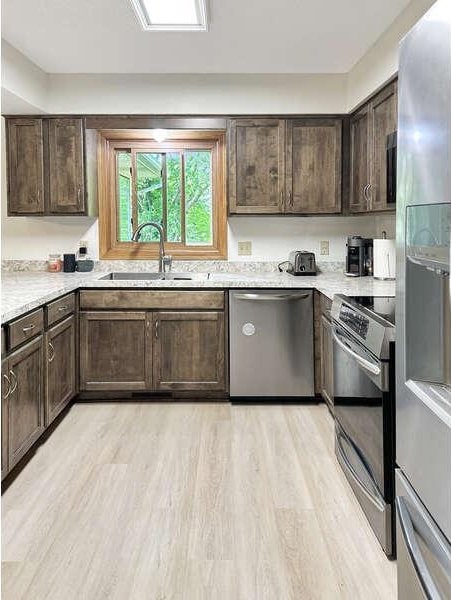 861 Lake Susan Dr, Chanhassen, MN 55317 - kitchen featuring appliances with stainless steel finishes, dark brown cabinetry, light wood finished floors, and light countertops
