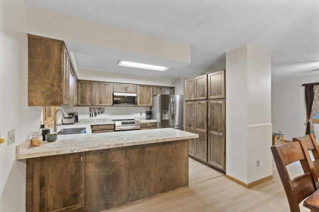 861 Lake Susan Dr, Chanhassen, MN 55317 - kitchen featuring appliances with stainless steel finishes, a peninsula, light wood-style floors, and light countertops