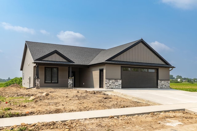 1202 15th St NE, Kasson, MN 55944 - view of front of property featuring an attached garage, concrete driveway, stone siding, and board and batten siding