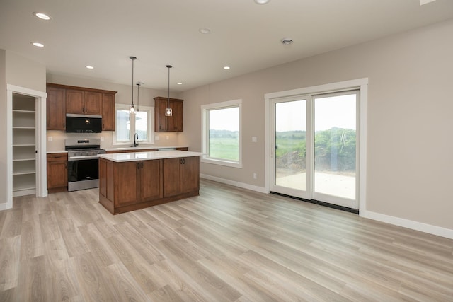1202 15th St NE, Kasson, MN 55944 - kitchen with stainless steel appliances, a sink, light countertops, a kitchen island, and light wood-type flooring