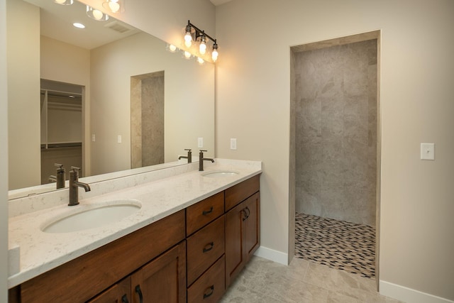 1202 15th St NE, Kasson, MN 55944 - bathroom with double vanity, a tile shower, baseboards, tile patterned floors, and a walk in closet