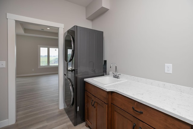 1202 15th St NE, Kasson, MN 55944 - laundry room featuring stacked washer / drying machine, a sink, light wood-type flooring, and baseboards