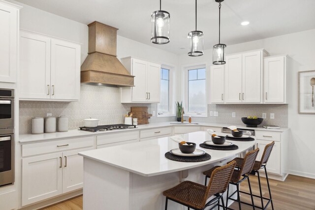 10625 29th St NE, Saint Michael, MN 55376 - kitchen with custom exhaust hood, stainless steel gas cooktop, a kitchen bar, light countertops, and white cabinetry