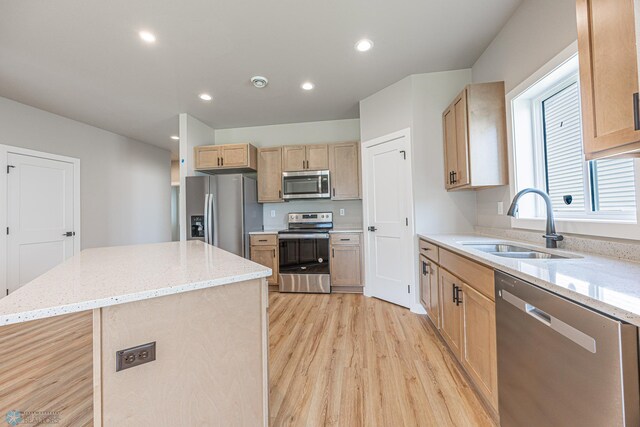 6614 68th St S, Horace, ND 58047 - kitchen featuring stainless steel appliances, light brown cabinetry, light wood-style floors, a kitchen island, and light stone countertops
