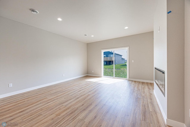6614 68th St S, Horace, ND 58047 - spare room featuring light wood finished floors, a glass covered fireplace, recessed lighting, heating unit, and a smoke detector