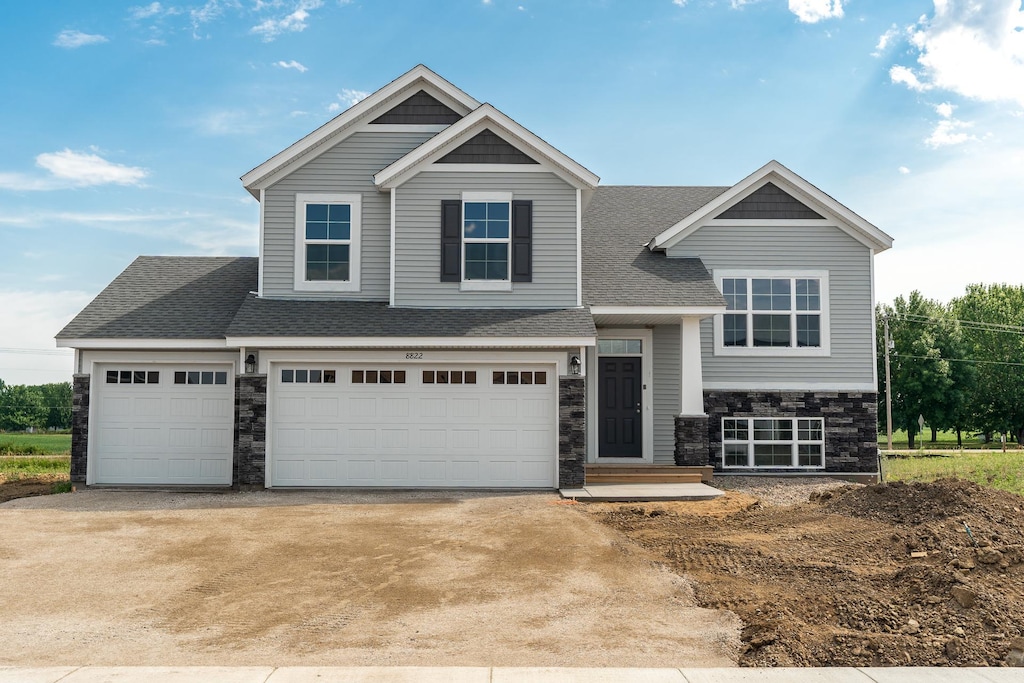 19919 English Ln N, Forest Lake, MN 55025 - view of front of home featuring stone siding, roof with shingles, concrete driveway, and an attached garage