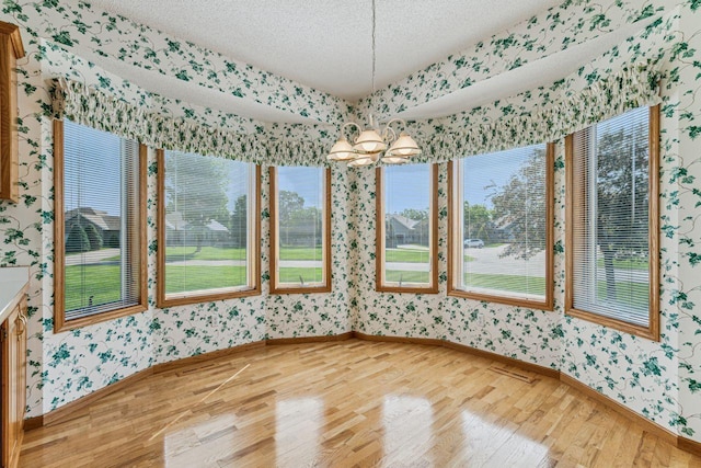 917 133rd Ln NE, Ham Lake, MN 55304 - unfurnished dining area with wallpapered walls, baseboards, light wood-style flooring, a chandelier, and a textured ceiling