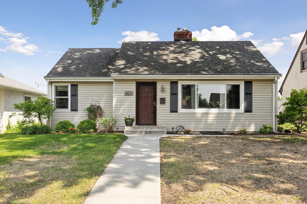 4416 Zenith Ave N, Robbinsdale, MN 55422 - cape cod house featuring a chimney, a front yard, and roof with shingles