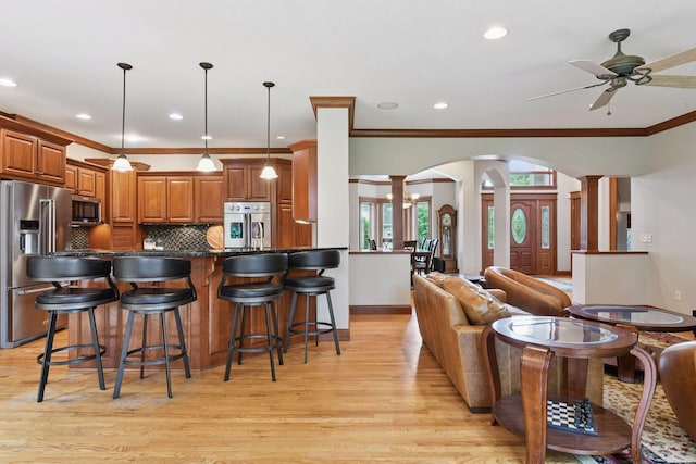 2906 Butternut Dr, Chaska, MN 55318 - kitchen with decorative columns, stainless steel appliances, ceiling fan, brown cabinets, and light wood-style flooring